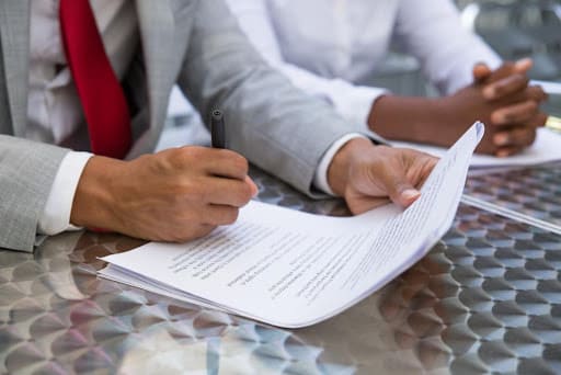 Advogado com papéis nas mãos, assinando um contrato, simbolizando as multas tributárias.
