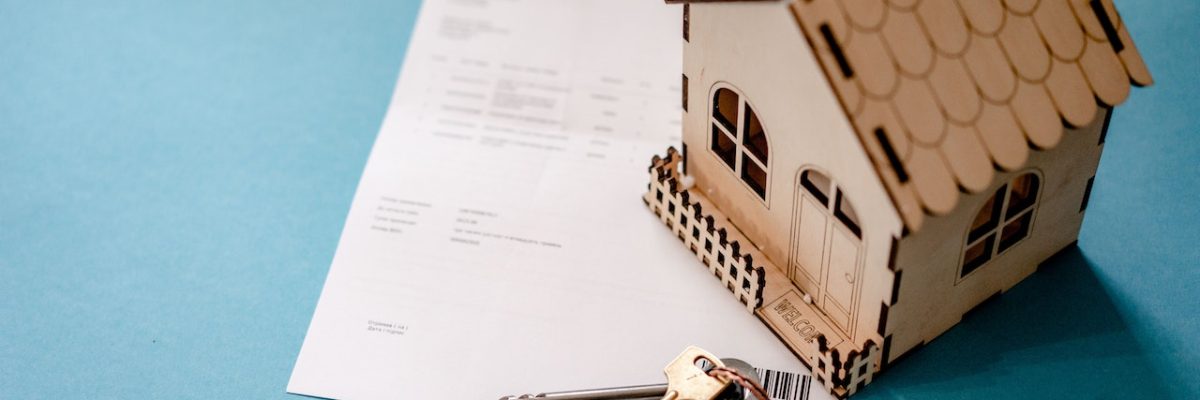 Imagem com contrato, chaves e uma pequena casa de madeira, simbolizando o contrato de aluguel vencido.